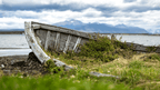 Old wooden boat on Patagonian shore with mountains in background, seen during the 9-day Blue Heart Adventure hiking tour. Rustic charm in remote landscapes.