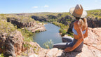Woman overlooks Katherine Gorge from cliff on Kakadu Katherine Gorge Tour | 4-Day Comfort Travel. Scenic lookout over river canyon.
