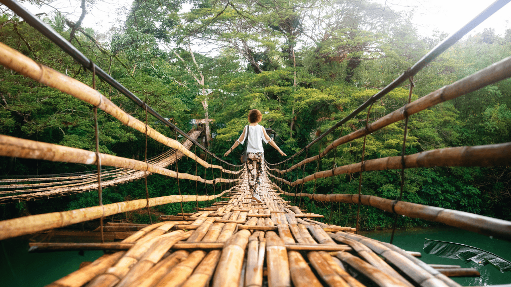 Child crossing a bamboo hanging bridge in Bohol, eco-adventure in Philippines Travel Tours - Icons of the Philippines.