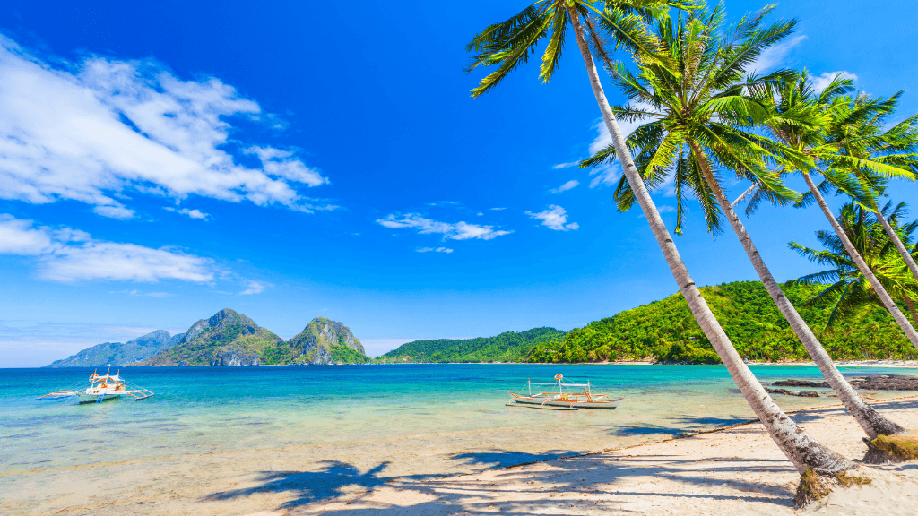 Tropical beach with palm trees and boats in El Nido, featured in Philippines Travel Tours - Icons of the Philippines | 10/14/23 Days.