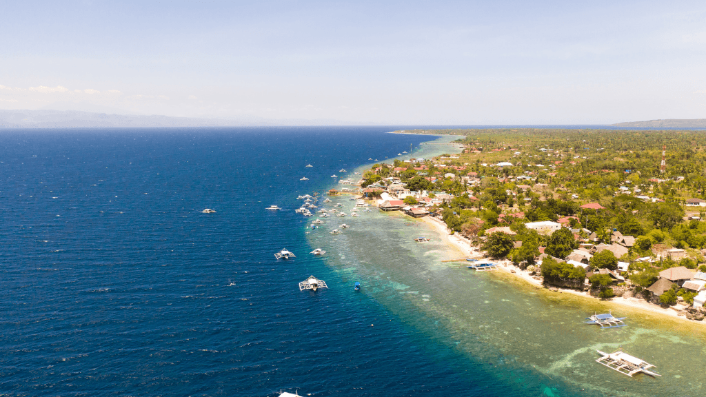 Aerial view of Moalboal coastline with boats, diving hotspot in Philippines Travel Tours - Icons of the Philippines | 10/14/23 Days.