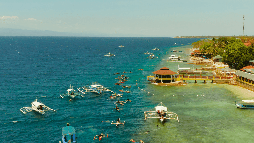 Snorkelers and boats along Moalboal coast, marine adventure in Philippines Travel Tours - Icons of the Philippines.