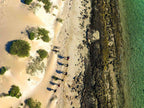 Aerial view of a group hiking along the sandy shore and rocky coastline of Ningaloo, showcasing adventure and nature.