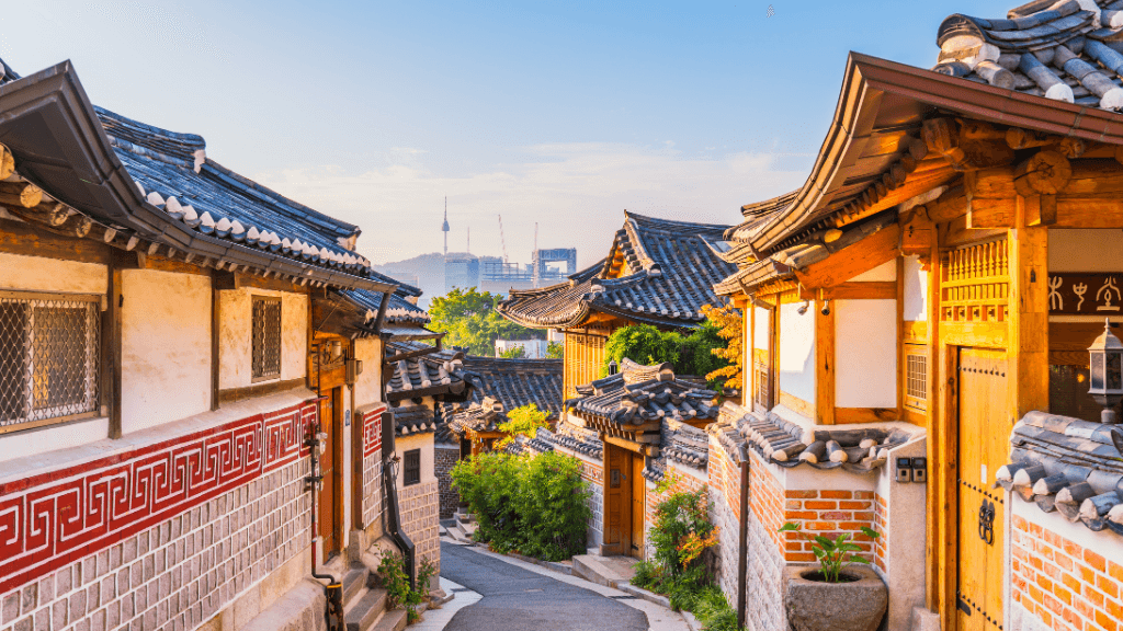 Traditional Korean houses with tiled roofs and wooden doors in a village setting.