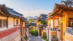 Traditional Korean houses with tiled roofs and wooden doors in a village setting.