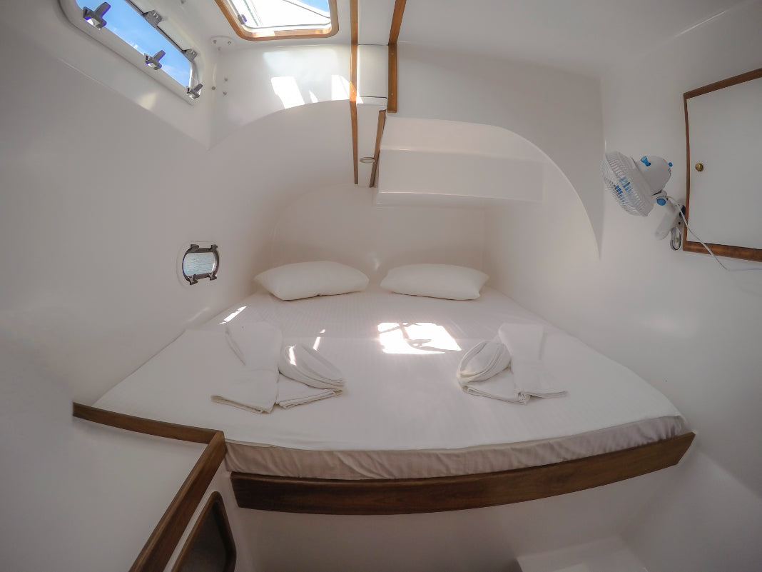 Minimalist white cabin with double bed on catamaran. Explore Sri Lanka - Land & Sea Tour Options includes cozy onboard accommodations.