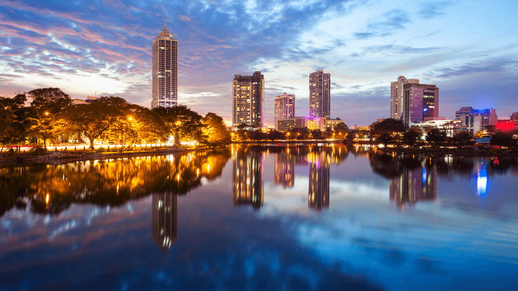 Colombo city skyline at dusk reflecting on Beira Lake, featured in the 12-day Sri Lanka spice gardens and coast highlights tour.