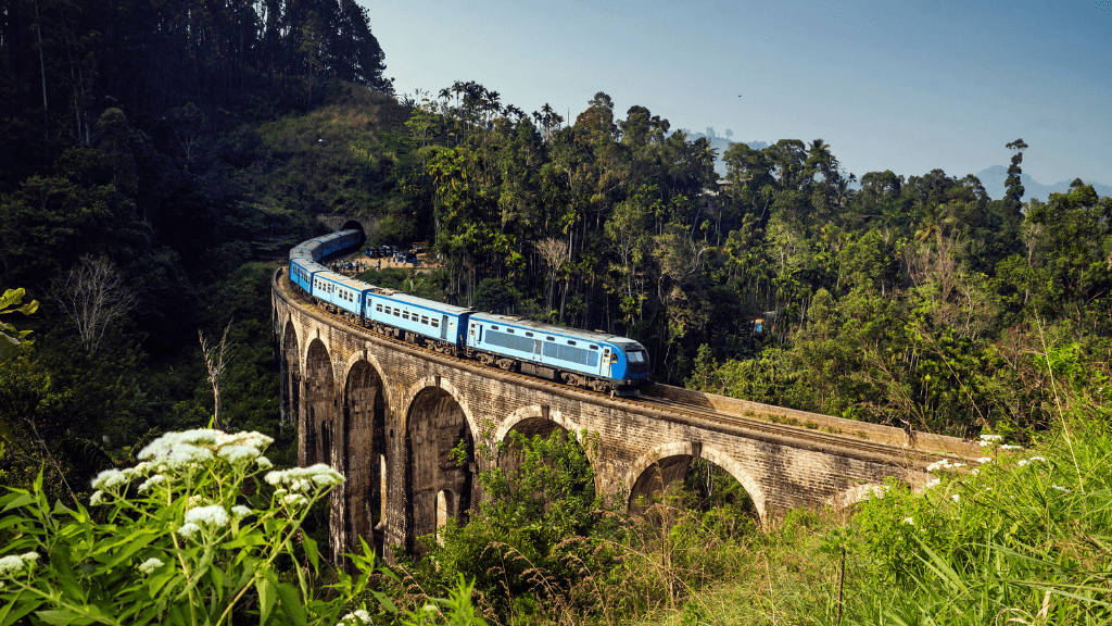 Blue train crossing Nine Arches Bridge in lush forest, a must-see on the 12-day Sri Lanka spice gardens and coast tour.