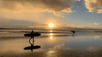 Surfer walking at sunrise in Byron Bay, part of East Coast Australia tour. Surf culture on 8-day Sydney to Brisbane itinerary.