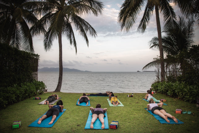 Yoga session by the sea under palm trees, a relaxing activity on the Angkor to Islands 16-Day Tour - Khmer Culture to Thai Coasts.