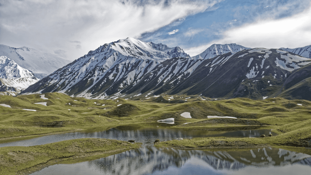 Snow-dusted green hills and alpine lakes in Kyrgyzstan, ideal for trekking on the Silk Road Cities Tour - Central Asia Adventure.
