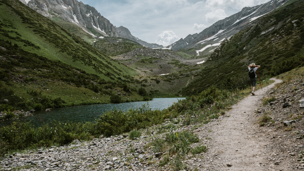 Solo hiker on a trail in the Fann Mountains, Tajikistan, enjoying nature on the Silk Road Cities Tour - Central Asia Adventure.