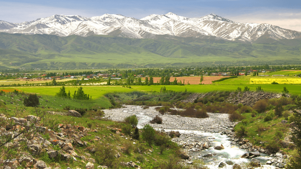 Mountain valley with river and green fields in Kyrgyzstan, a scenic view on the Silk Road Cities Tour - Central Asia Adventure.