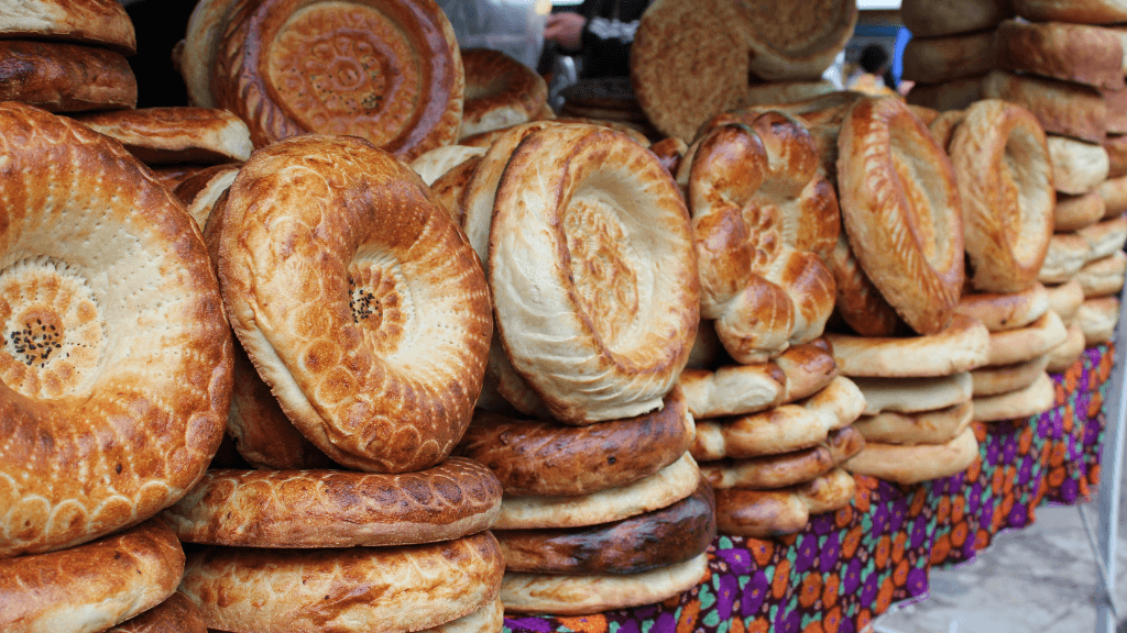 Stacks of traditional Uzbek bread at a local market, a culinary highlight of the Silk Road Cities Tour - Central Asia Adventure.