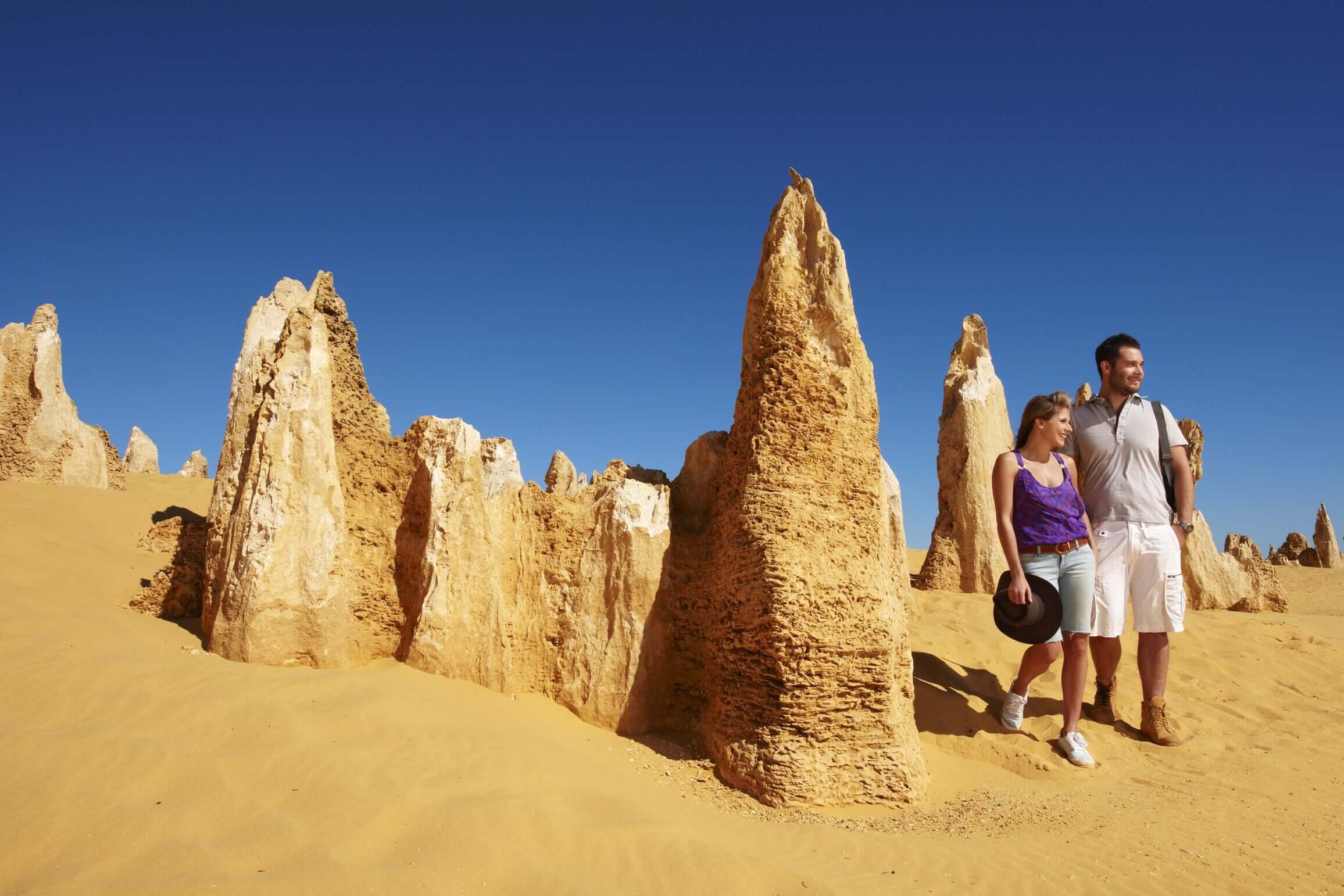 Couple exploring Pinnacles Desert rock formations during West Coast Road Trip. Unique geological site in Western Australia.