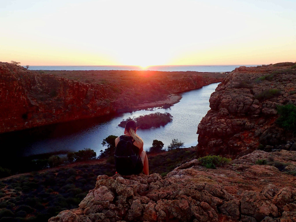 Hiker overlooking Cape Range gorge at sunset, a scenic hike included in the Ningaloo Safari 3-Day Kayak & Snorkel Tour.