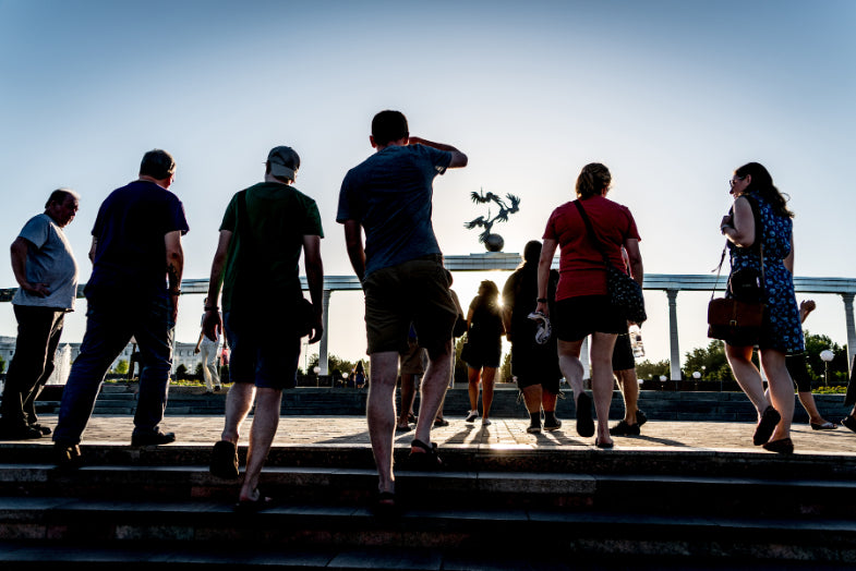 Tour group silhouetted against sunset at a monument in Tashkent, Uzbekistan, part of the cultural journey on the 14-23 Day Central Asia Silk Road Tour.