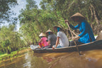 Tourists paddling through a lush mangrove forest in Vietnam. Nature excursion included in Vietnam Hiking and Cycling Tour.