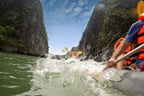 Kayakers paddling through narrow limestone cliffs in Vietnam. Thrilling water activity on Vietnam Hiking and Cycling Tour.