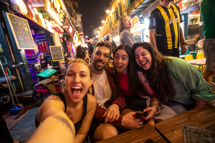 Group selfie at a lively night market in Vietnam. Social nightlife experience on Vietnam Hiking and Cycling Tour.