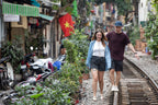 Couple walking along train tracks in Hanoi’s café-lined street. Romantic stroll on Vietnam Hiking and Cycling Tour.