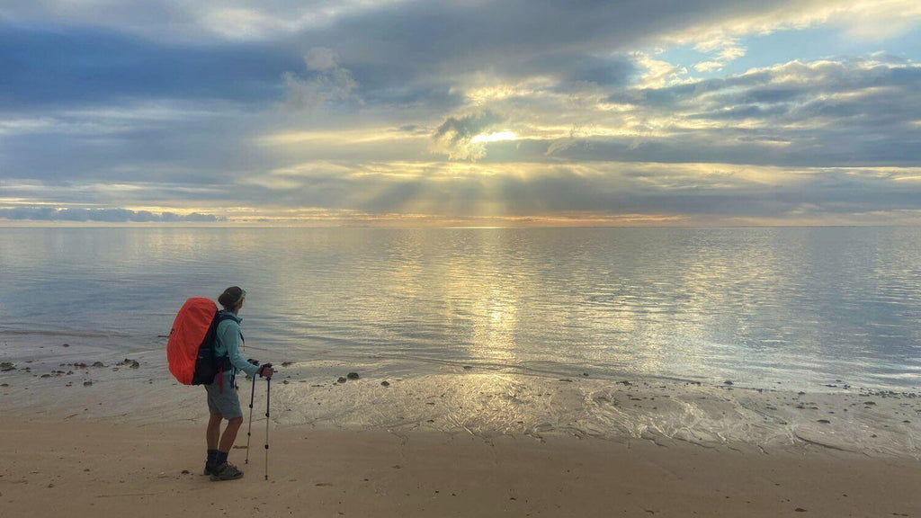 Hiker watching sunrise over calm ocean on Ningaloo Reef Kayak & Snorkel Tour. Great for trekking and nature-focused experiences.
