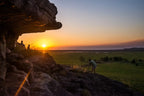 Sunset view from rock ledge showcasing adventure seekers in Australia's Top End wilderness.