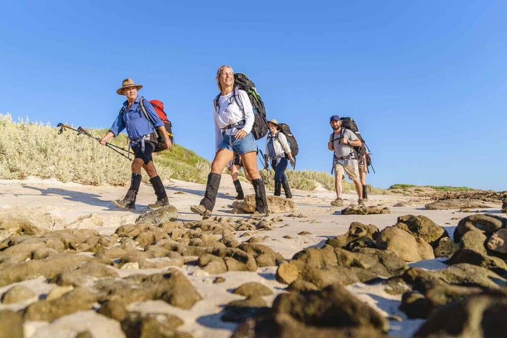 Adventure seekers hiking along the rugged beach during a group trek in Western Australia.