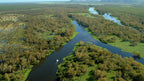 Aerial view of winding river through wetlands at Kakadu Litchfield Camping Adventure - 3-Day Tour. Lush green floodplains and boat cruising.