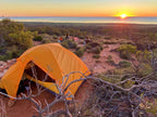 Sunset view over the Ningaloo Coast with an orange tent set in rugged terrain, perfect for adventure tours.