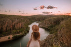 A traveler in a straw hat admires the stunning landscape of a river canyon at sunset in Australia.