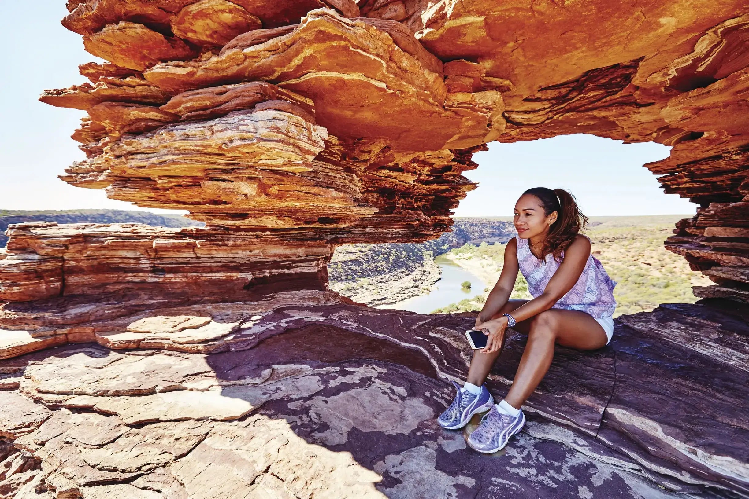 Traveler sitting at Nature’s Window in Kalbarri National Park on West Coast Road Trip. Iconic rock formation and hiking destination in Western Australia.