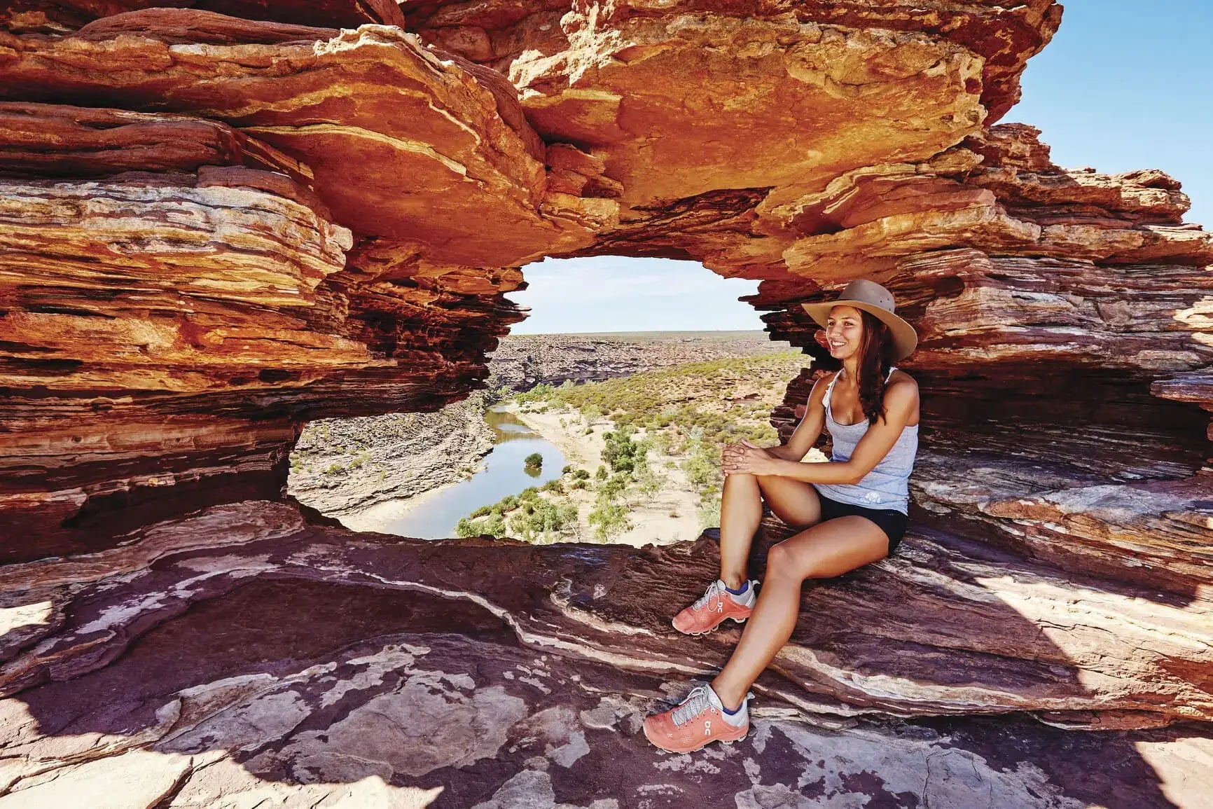 Traveler relaxing at Nature’s Window in Kalbarri National Park on West Coast Road Trip. Scenic hiking spot in Western Australia.